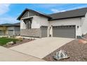 Charming home featuring a stone facade, two-car garage, and well-maintained landscaping at 5492 Woodroot Pt, Castle Rock, CO 80104