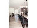 Open concept kitchen and living area with island seating and modern finishes at 5492 Woodroot Pt, Castle Rock, CO 80104