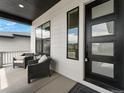 Inviting porch area with stylish seating, modern black door, and ample natural light at 5492 Woodroot Pt, Castle Rock, CO 80104