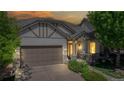 Dusk view of charming home with a two-car garage, covered porch, and manicured landscaping  at 6187 Reed Way, Arvada, CO 80003