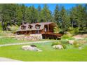 Charming log home with a deck, surrounded by lush greenery, stone accents, and rustic charm at 60 N County Highway 67, Sedalia, CO 80135