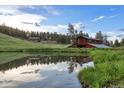 Scenic pond reflecting the sky and trees, nestled in a landscape with a charming building in the background at 60 N County Highway 67, Sedalia, CO 80135