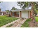 Charming one-story red brick home featuring an attached garage and mature landscaping at 1325 Geneva St, Aurora, CO 80010