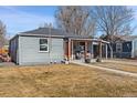 Cozy gray home featuring an inviting front porch and well-maintained front yard at 6835 W 55Th Pl, Arvada, CO 80002