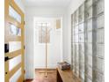 Sunlit foyer with glass block window, modern bench, and sunny yellow door at 3925 Newland St, Wheat Ridge, CO 80033