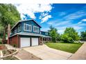 A blue two-story home features a two-car garage, brick accents, and a well-maintained lawn at 4645 W Temple Pl, Denver, CO 80236