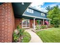 Inviting front porch with brick siding, American flag, and garden filled with colorful flowers at 4645 W Temple Pl, Denver, CO 80236