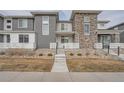 Townhome features stone accents, gray siding, and a front walkway leading to the entrance at 16700 Alzere Pl, Parker, CO 80134