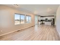 Open-concept living room with natural light, wood floors, and seamless flow to a modern kitchen at 6646 Merrimack Dr, Castle Pines, CO 80108