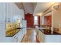 Modern white kitchen with granite countertops and exposed brick at 3233 Osage St # 2A, Denver, CO 80211