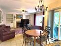 Open living room with a fireplace, wood floors, ceiling fan, and a dining table and a sliding door to a patio at 15292 E Hialeah Pl, Aurora, CO 80015