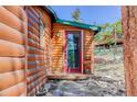 Cozy cabin entrance with a red-framed glass door and a charming welcome sign at 6743 Wild Rose Ln, Evergreen, CO 80439