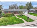 Charming brick home featuring a well-manicured lawn, curved walkway, and mature landscaping at 798 Alkire St, Lakewood, CO 80401