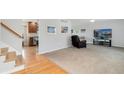 Bright living room with plush carpet, ceiling fan, and open access to the kitchen and stairs at 7276 W 83Rd Way, Arvada, CO 80003