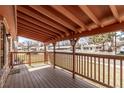 Covered front porch featuring a wood deck, railing, and view of the neighborhood at 7720 Kendall St, Arvada, CO 80003