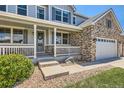 Inviting front porch with white railings, gray siding, a decorative wreath, and manicured landscaping at 22197 E Stroll Ave, Parker, CO 80138