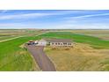 Aerial view of a tan home with red shutters surrounded by green and brown fields at 14551 N Harback Rd, Keenesburg, CO 80643
