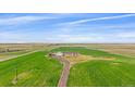 An aerial view of a home surrounded by fields and a long dirt driveway at 14551 N Harback Rd, Keenesburg, CO 80643