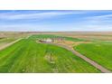 An aerial view of a rural property featuring green fields and a long driveway at 14551 N Harback Rd, Keenesburg, CO 80643