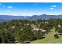 Beautiful mountain views surround a home nestled amongst towering pine trees and other high-end properties at 1621 Baneberry Ln, Golden, CO 80401