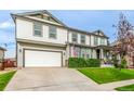 Well-maintained home with a two-car garage, driveway, manicured lawn, and welcoming front porch at 12330 Village E Cir, Commerce City, CO 80603