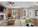 Bright living room featuring exposed brick, a decorative fireplace, large windows, and hardwood floors at 3254 Newton St, Denver, CO 80211