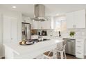 Bright and airy kitchen boasts stainless steel appliances, an island with seating and clean white cabinetry at 6163 W 76Th Ave, Arvada, CO 80003