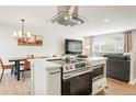 Open floor plan kitchen features an island with modern stainless steel appliances and breakfast bar seating at 6163 W 76Th Ave, Arvada, CO 80003