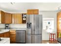 Bright kitchen featuring stainless steel refrigerator and wooden cabinetry at 5211 Dover St, Arvada, CO 80002