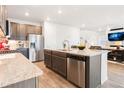 Open-concept kitchen with stainless steel appliances, granite countertops, and an island that opens to the living area at 8582 Cheraw St, Littleton, CO 80125