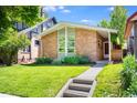 Inviting single-story brick home with a green lawn, mature trees, and a tidy garden bed at 1622 Monroe St, Denver, CO 80206