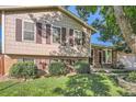 A tan two-story home with brown shutters and brick accents presents a cozy facade at 4664 S Zang St, Morrison, CO 80465