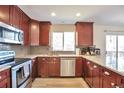Well-lit kitchen featuring cherry cabinets, stainless steel appliances, gray backsplash, and great counter space at 9889 Aftonwood St, Highlands Ranch, CO 80126