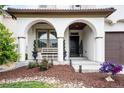 Inviting front porch showcasing arched entryways, a bench, decorative plants, and manicured garden beds at 15205 W Baker Ave, Lakewood, CO 80228