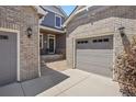 View shows the driveway and garage doors and the exterior brick finish details at 8677 S Buchanan Way, Aurora, CO 80016