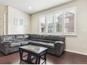 Bright living room featuring dark hardwood floors, a sectional couch, and natural light at 6765 S Old Hammer Ct, Aurora, CO 80016