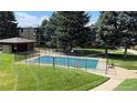 Community fenced swimming pool surrounded by grass and mature trees at 2281 S Vaughn Way # 118A, Aurora, CO 80014