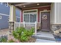Inviting front porch with stylish door, stone accents, and a well-manicured garden at 17855 E 103Rd Ave, Commerce City, CO 80022