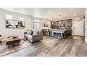 Open-concept living room with a modern kitchen and sleek hardwood floors at 17855 E 103Rd Ave, Commerce City, CO 80022