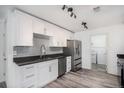 Modern kitchen with white cabinets, gray backsplash, stainless steel appliances, and wood-look flooring at 19153 E 51St Ave, Denver, CO 80249