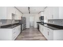 Modern kitchen featuring stainless steel appliances, subway tile backsplash, dark countertops, and wood floor at 19153 E 51St Ave, Denver, CO 80249