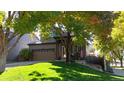 Landscaped front yard of a charming home with mature trees offering shade and curb appeal at 6898 W Rockland Pl, Littleton, CO 80128