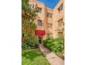 Charming apartment building entrance with red awning and mature landscaping at 1100 Colorado Blvd # 305, Denver, CO 80206