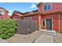 Detailed view of the red townhome's entry, showcasing landscaping and modern door at 1775 Aspen Meadows Cir, Denver, CO 80260