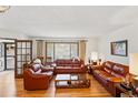 Cozy living room featuring hardwood floors, comfortable leather sofas, and ample natural light at 7590 E Easter Pl, Centennial, CO 80112