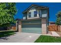 Two-story home featuring a front-facing two car garage, mature landscaping, and a brick facade at 20445 Mitchell Pl, Denver, CO 80249