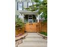 Inviting front entrance with steps leading to the covered porch, wood gate and colorful flowers at 2098 N Clarkson St, Denver, CO 80205