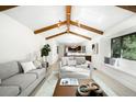 Bright living room with vaulted ceilings, wooden beams, a skylight, comfortable seating, and an open view into the kitchen at 7308 S Steele Cir, Centennial, CO 80122
