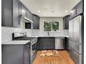 The kitchen features modern stainless steel appliances, gray cabinets, hardwood floors and bright, natural light at 495 Quebec St, Denver, CO 80220