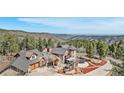 Beautiful home featuring stone exterior, a turret, and an outdoor patio overlooking scenic mountain views and lush tree coverage at 12555 Critchell Ln, Littleton, CO 80127